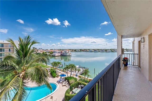 balcony with a water view and view of pool area