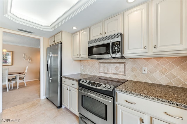 kitchen with stainless steel appliances, dark stone countertops, crown molding, backsplash, and light carpet