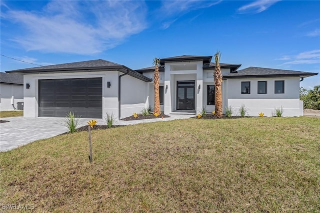 prairie-style home with a garage, stucco siding, driveway, and a front yard
