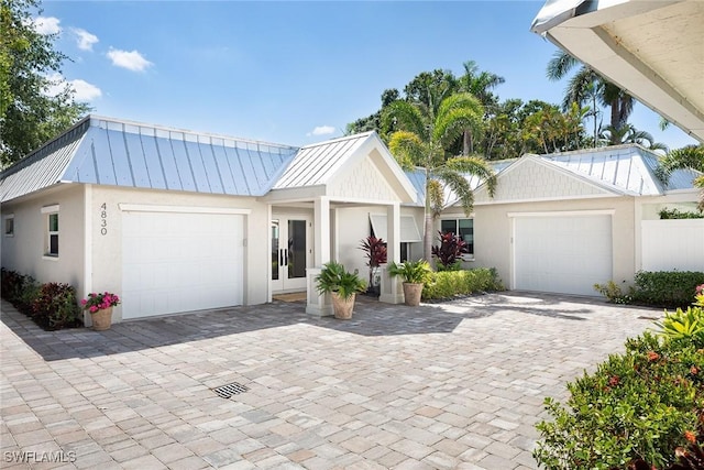 view of front of property with a standing seam roof, metal roof, stucco siding, and a garage