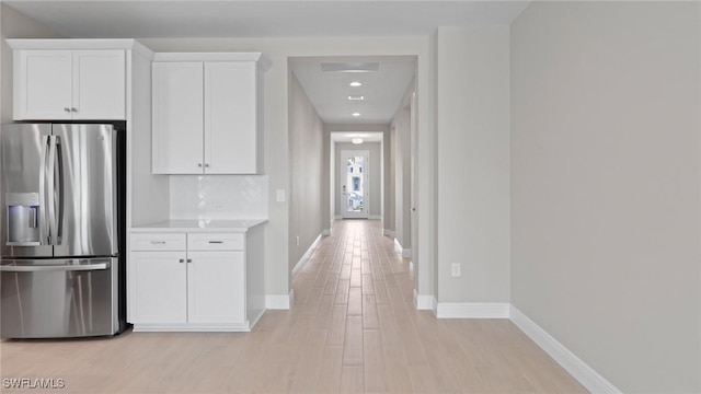 17825 Summerland Key Ct, Fort Myers, FL 33908 - kitchen with stainless steel refrigerator with ice dispenser, baseboards, white cabinets, light wood-type flooring, and light countertops