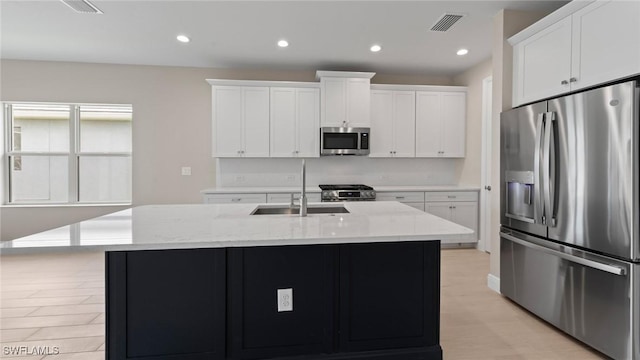17825 Summerland Key Ct, Fort Myers, FL 33908 - kitchen featuring appliances with stainless steel finishes, a sink, white cabinets, light stone countertops, and a center island with sink