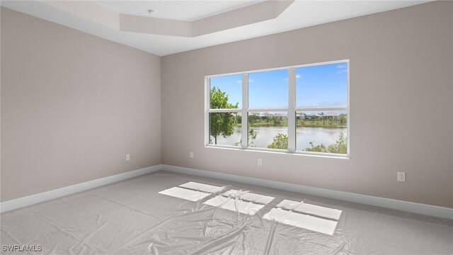 17825 Summerland Key Ct, Fort Myers, FL 33908 - unfurnished room featuring light colored carpet, baseboards, a water view, and a raised ceiling