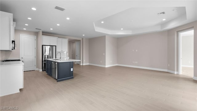 17825 Summerland Key Ct, Fort Myers, FL 33908 - kitchen with recessed lighting, a tray ceiling, light countertops, a center island with sink, and white cabinetry