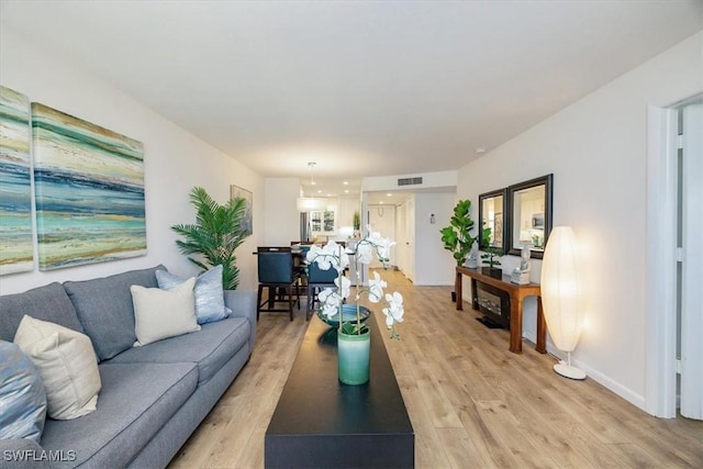 living area featuring visible vents, baseboards, and light wood-style floors