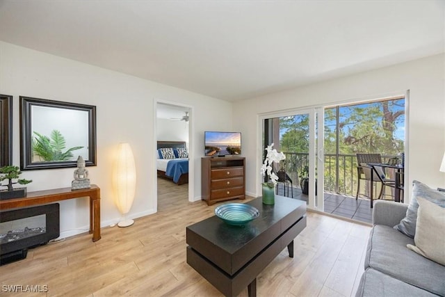 living room with baseboards, light wood-type flooring, and ceiling fan