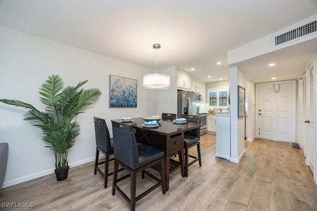 dining space with baseboards, visible vents, light wood finished floors, and recessed lighting