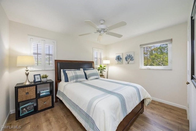 bedroom featuring baseboards, wood finished floors, and multiple windows