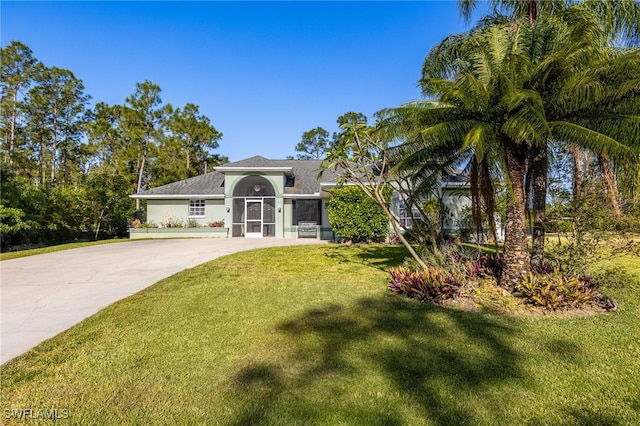 view of front of house featuring driveway, a front yard, and stucco siding