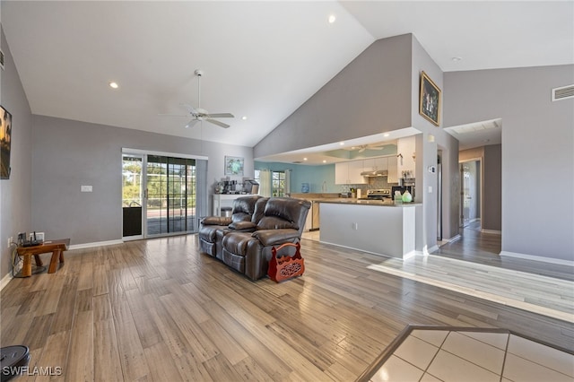 living room featuring light wood-style flooring, ceiling fan, baseboards, recessed lighting, and high vaulted ceiling