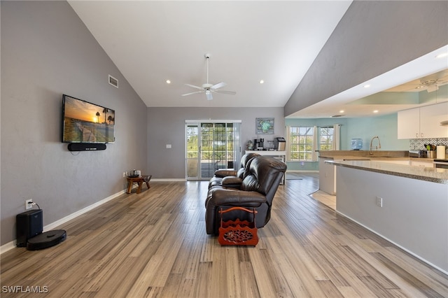 living room with light wood finished floors, a ceiling fan, visible vents, and high vaulted ceiling