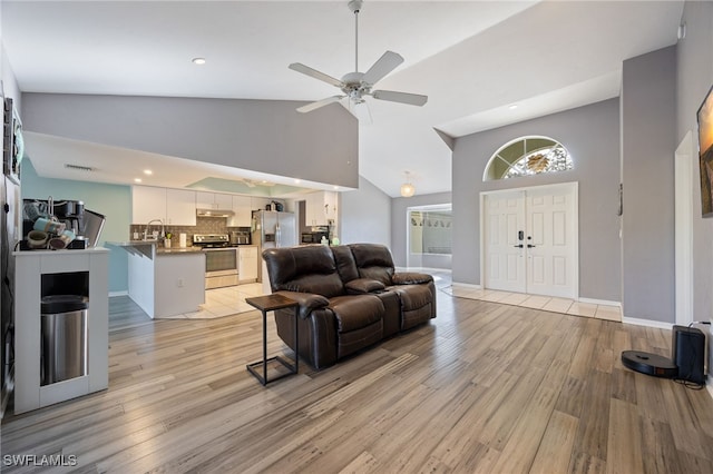 living room with visible vents, ceiling fan, light wood-type flooring, and high vaulted ceiling