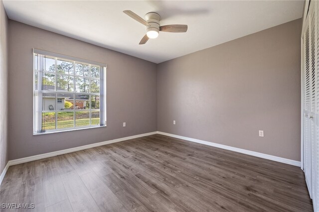 unfurnished room with a ceiling fan, dark wood finished floors, and baseboards