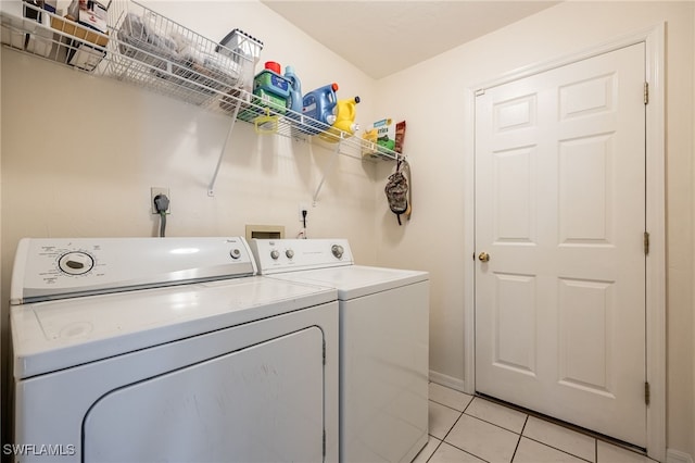 laundry area with light tile patterned flooring, washing machine and clothes dryer, laundry area, and baseboards