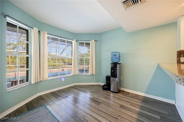 unfurnished room featuring baseboards, visible vents, and wood finished floors