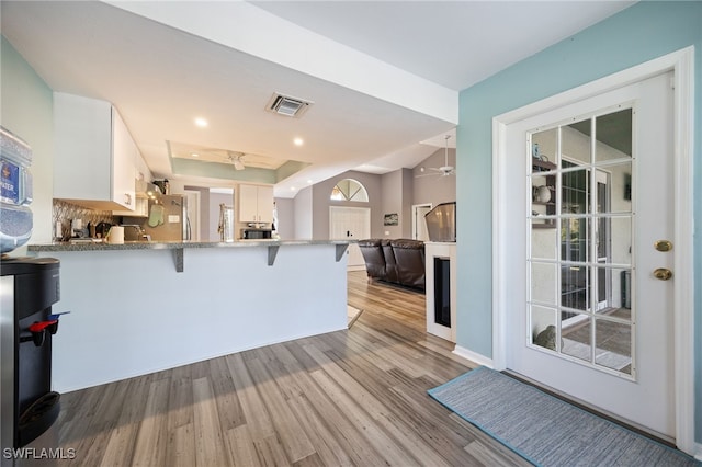kitchen with light wood-style flooring, ceiling fan, visible vents, a peninsula, and a kitchen breakfast bar