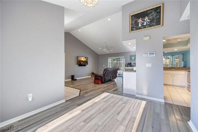 living area featuring high vaulted ceiling, ceiling fan, light wood finished floors, and plenty of natural light