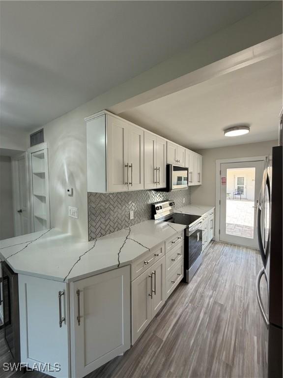 530 Broad Ave S Unit 530, Naples, FL 34102 - kitchen featuring tasteful backsplash, light stone countertops, freestanding refrigerator, white cabinetry, and stainless steel electric stove