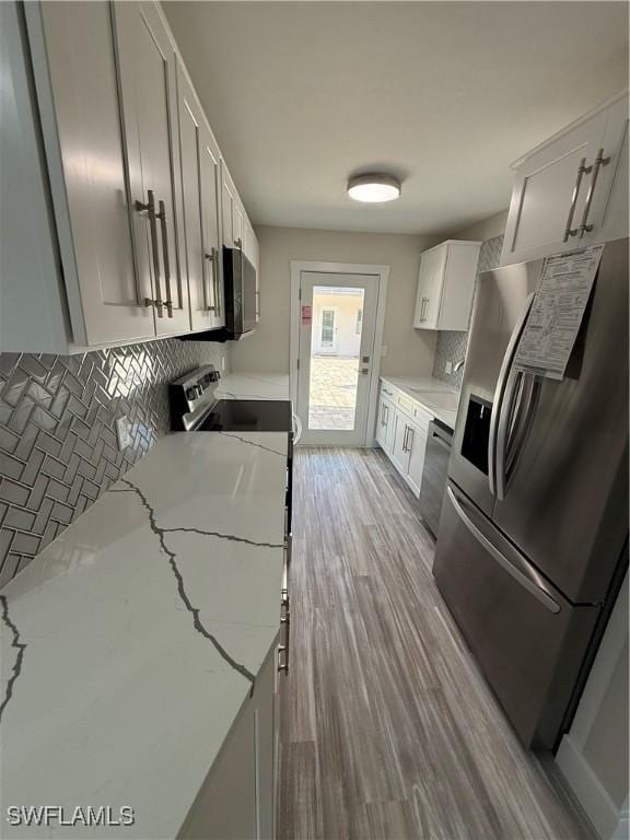 530 Broad Ave S Unit 530, Naples, FL 34102 - kitchen with backsplash, light stone counters, white cabinets, appliances with stainless steel finishes, and wood finished floors