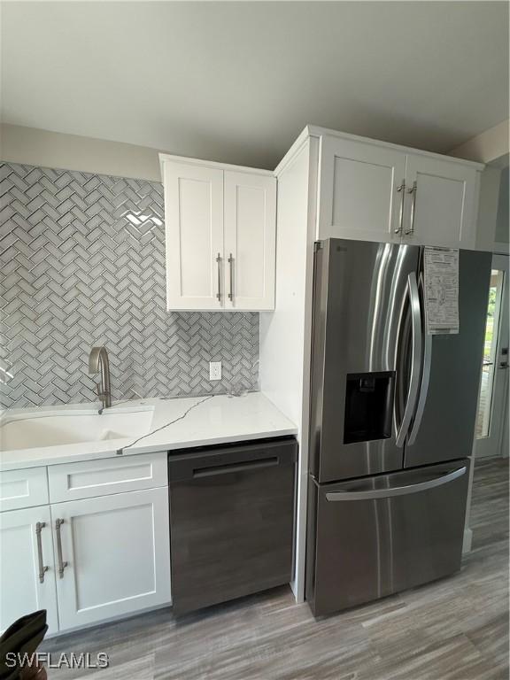 530 Broad Ave S Unit 530, Naples, FL 34102 - kitchen with stainless steel fridge with ice dispenser, backsplash, dishwasher, a sink, and white cabinetry