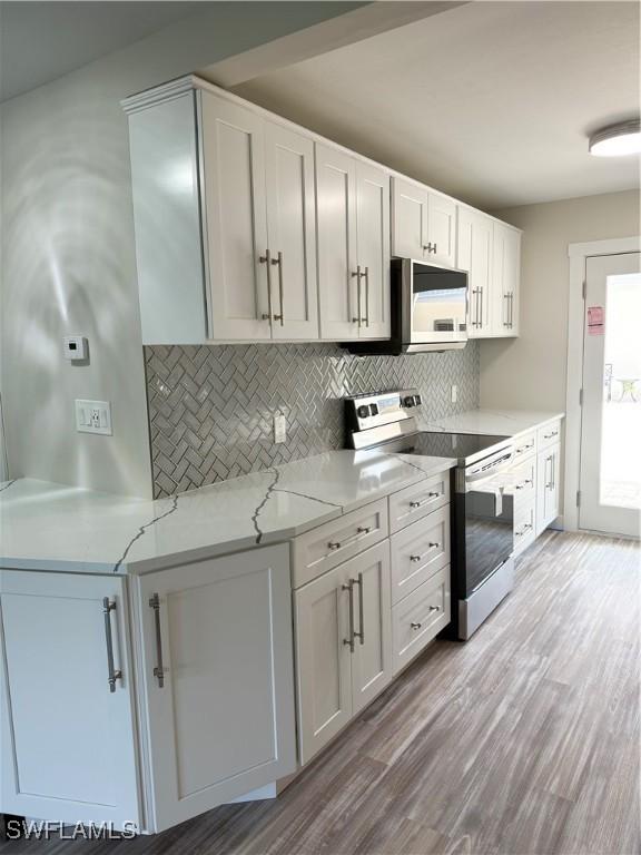 530 Broad Ave S Unit 530, Naples, FL 34102 - kitchen with light wood finished floors, decorative backsplash, stainless steel range with electric stovetop, and white microwave