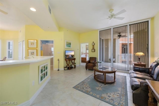 living room with baseboards, visible vents, light tile patterned floors, and ceiling fan