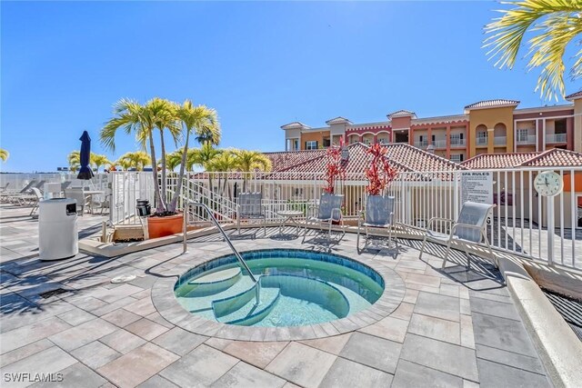 view of swimming pool featuring fence and a community hot tub