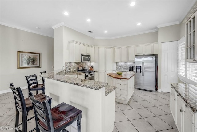 8442 Mallards Way, Naples, FL 34114 - kitchen featuring a peninsula, a kitchen bar, a center island, appliances with stainless steel finishes, and backsplash