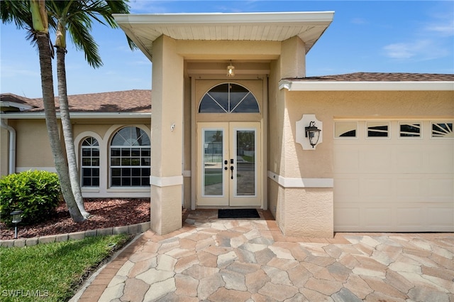 entrance to property with a garage, stucco siding, and french doors