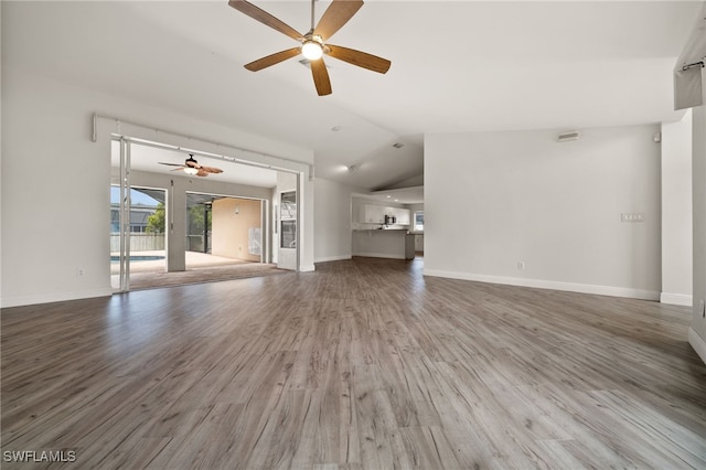 unfurnished living room featuring baseboards, a ceiling fan, wood finished floors, and lofted ceiling