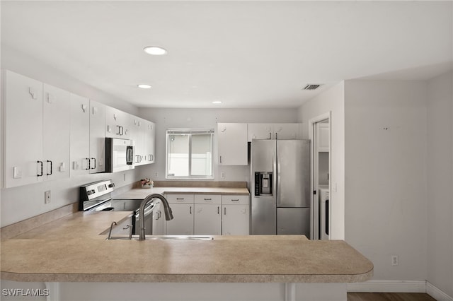 kitchen featuring a peninsula, recessed lighting, light countertops, a sink, and appliances with stainless steel finishes