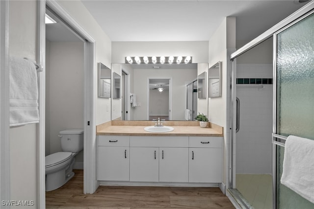 full bath with toilet, a shower stall, wood finished floors, and vanity