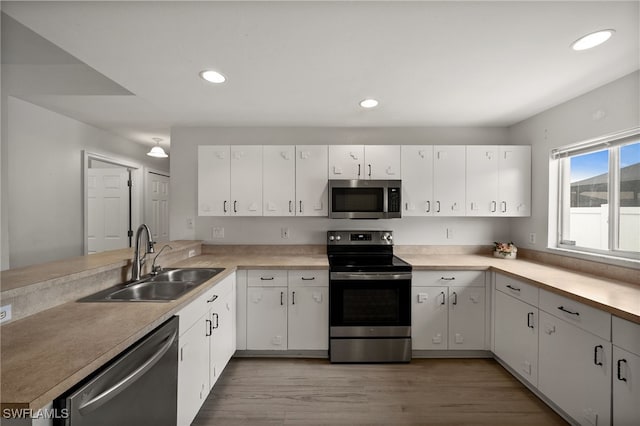 kitchen featuring light countertops, stainless steel appliances, a sink, and light wood-style floors