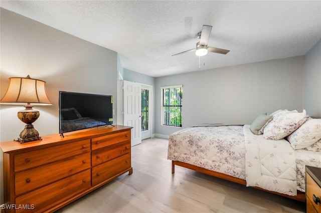 15177 Parkside Dr Unit 104, Fort Myers, FL 33908 - bedroom featuring light wood-style floors, access to exterior, baseboards, a ceiling fan, and a textured ceiling