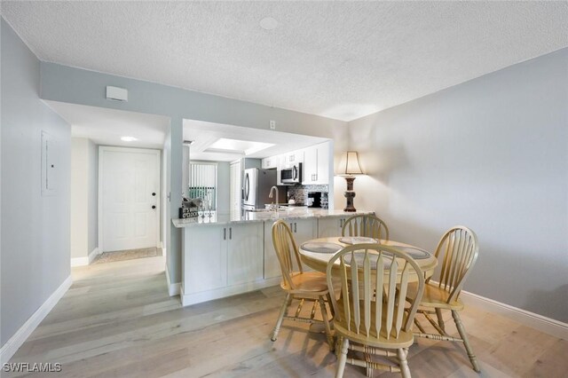 15177 Parkside Dr Unit 104, Fort Myers, FL 33908 - dining area featuring baseboards, light wood-style floors, and a textured ceiling