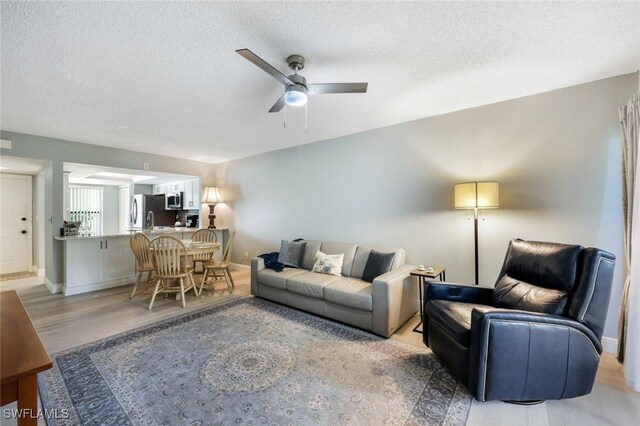 15177 Parkside Dr Unit 104, Fort Myers, FL 33908 - living room with baseboards, ceiling fan, a textured ceiling, and light wood finished floors