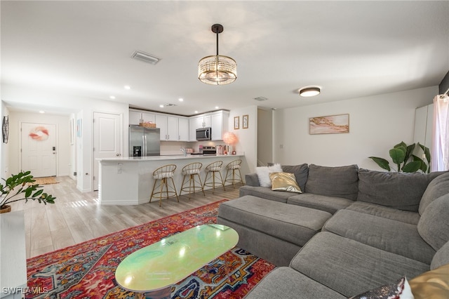 living area featuring an inviting chandelier, visible vents, recessed lighting, and light wood-style floors
