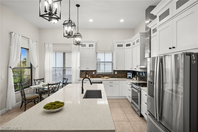 kitchen with a wealth of natural light, appliances with stainless steel finishes, an island with sink, and a sink