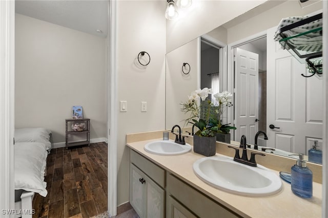 full bath featuring double vanity, wood finished floors, baseboards, and a sink