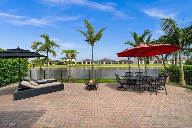 view of patio with fence, a fire pit, a residential view, and a water view