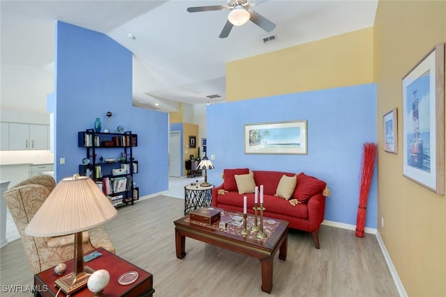 living room with baseboards, wood finished floors, ceiling fan, and vaulted ceiling
