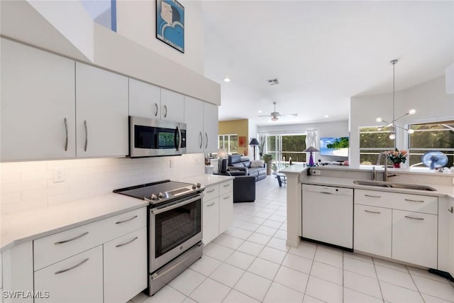 kitchen with a sink, decorative backsplash, white cabinetry, appliances with stainless steel finishes, and open floor plan