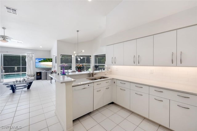 kitchen with a sink, decorative backsplash, white dishwasher, visible vents, and a peninsula