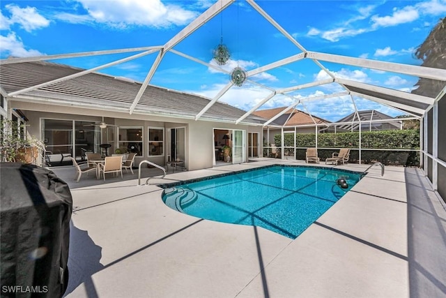 outdoor pool featuring glass enclosure, a patio area, and ceiling fan