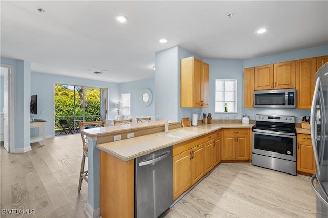 1305 Sweetwater Cv Unit 104, Naples, FL 34110 - kitchen featuring a wealth of natural light, stainless steel appliances, light wood-type flooring, and a sink