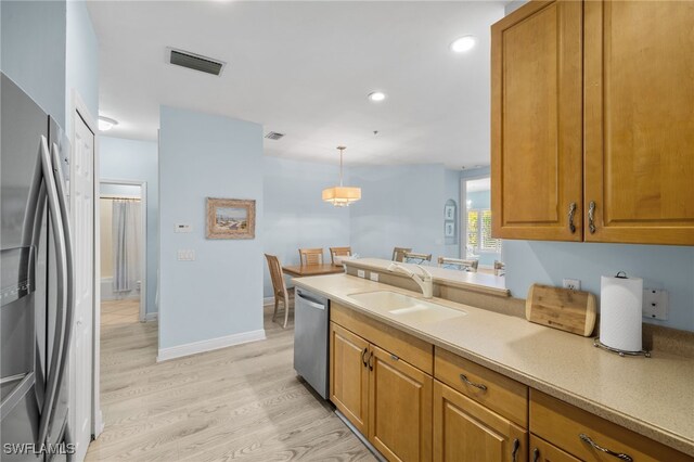 1305 Sweetwater Cv Unit 104, Naples, FL 34110 - kitchen with a sink, brown cabinetry, visible vents, light wood-style flooring, and appliances with stainless steel finishes
