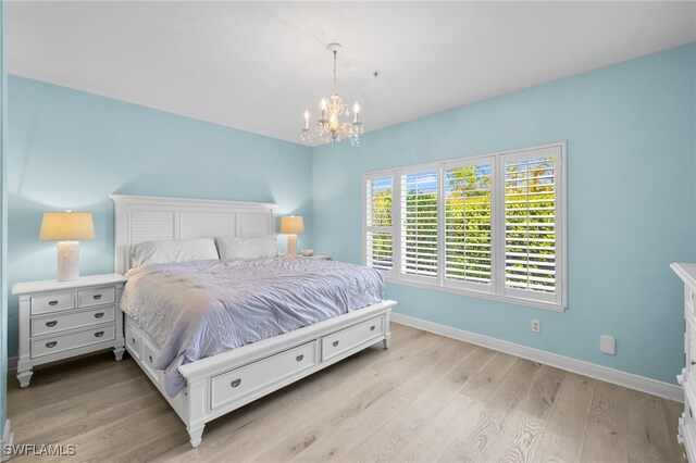 1305 Sweetwater Cv Unit 104, Naples, FL 34110 - bedroom featuring light wood-type flooring, a notable chandelier, and baseboards