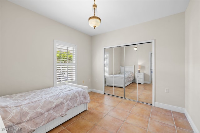 1305 Sweetwater Cv Unit 104, Naples, FL 34110 - bedroom featuring baseboards, light tile patterned floors, and a closet