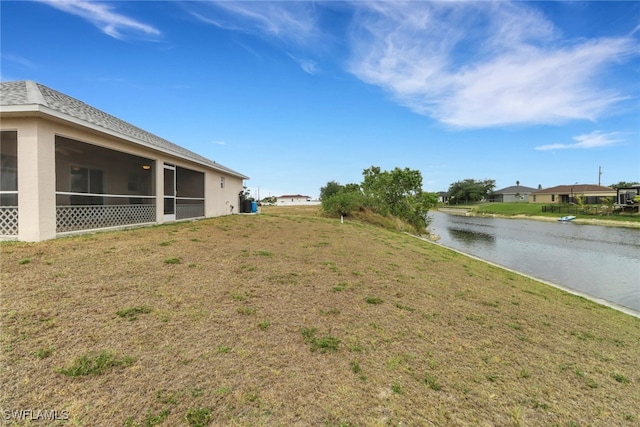 view of yard featuring a sunroom and a water view