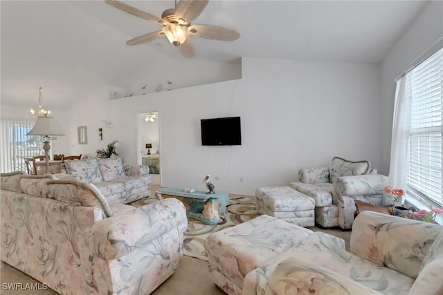 living area with lofted ceiling, ceiling fan with notable chandelier, and a healthy amount of sunlight
